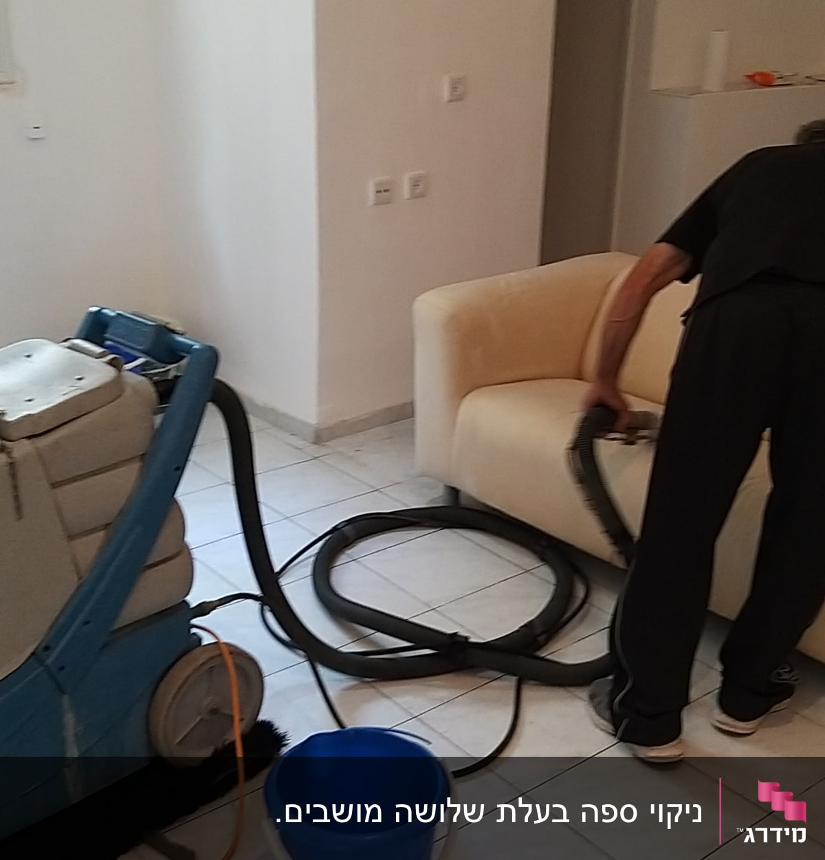 אדם מנקה ספה עם מכונת ניקוי ושואב אבק